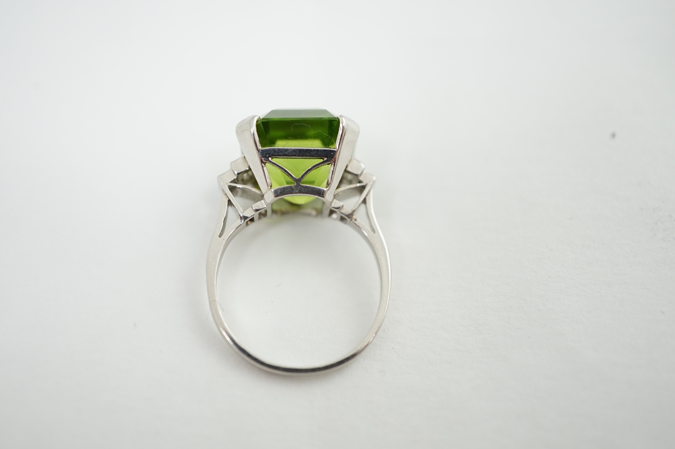 A 1920's platinum and single stone asscher cut peridot set dress ring, with four stone graduated baguette cut diamond set shoulders